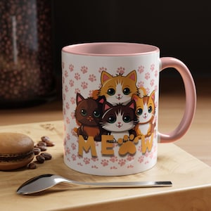 May include: White ceramic mug with a pink interior and handle, featuring a design of four cartoon cats and the word "MEOW" in gold letters. The mug is decorated with pink paw prints.