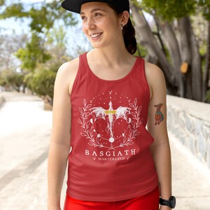 May include: Red vest top with a white graphic design featuring a winged creature, celestial elements, and the text "BASGIATH WAR COLLEGE". The top is worn with a black cap and red shorts.