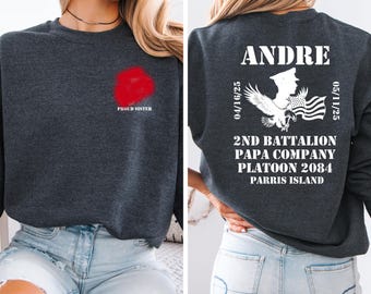May include: A charcoal grey sweatshirt with a red floral design and the text "PROUD SISTER" on the front. The back displays the name "ANDRE", military insignia, and text including "2ND BATTALION" and "PARRIS ISLAND".