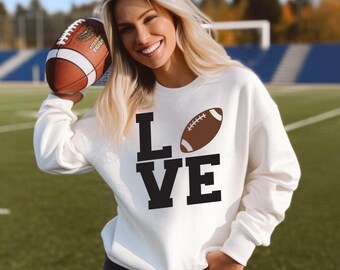 May include: White sweatshirt with a black graphic of the word "LOVE" with a brown football replacing the "O".