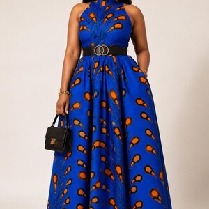 May include: A floor-length sleeveless dress in a vibrant blue fabric featuring a repeating orange and black feather-like pattern. The dress has a high neckline, a fitted bodice, and a full, pleated skirt cinched with a wide black belt.