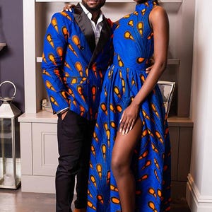 May include: A blue blazer with black lapels and a blue sleeveless high-neck dress, both featuring a vibrant orange and yellow teardrop pattern. The dress includes a floor-length skirt with a high side slit, while the blazer is paired with black trousers.