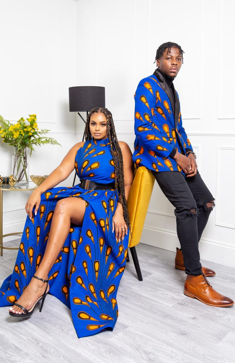 May include: A sleeveless blue dress with a high neckline, a black waist belt, and a high leg slit, featuring an orange and yellow teardrop pattern. A blue blazer with a black lapel and the same teardrop pattern, paired with black jeans.