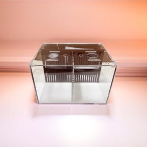 May include: A clear acrylic divided tank with a black divider and a black plastic top with holes. The tank is empty.