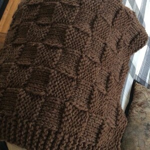 May include: A brown knitted throw blanket with a cable knit pattern.