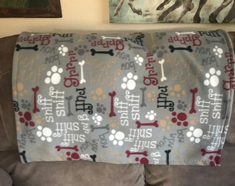 Könnte beinhalten: Graue Fleece-Decke mit einem Hunde-Motiv. Der Druck zeigt Pfotenabdrücke, Knochen und die Wörter "ruff", "sniff", "bow" und "mom".
