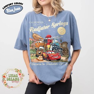 Pode incluir: Uma caneca de cer&acirc;mica branca com uma al&ccedil;a preta e o texto "But First, Coffee" em negrito preto. A caneca est&aacute; sobre uma superf&iacute;cie branca. A caneca tem aproximadamente 10 cm de altura.