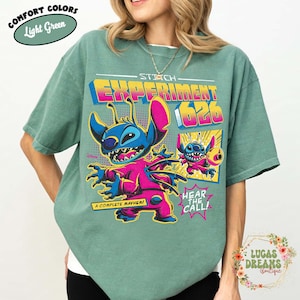 May include: Light green t-shirt featuring a colorful graphic of Stitch, Experiment 626, with the text "STITCH EXPERIMENT 626", and the phrases "A COMPLETE MAYHEM!" and "HEAR THE CALL!". The shirt is a comfort color.