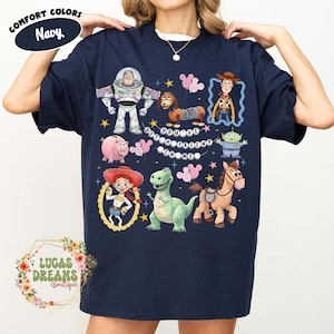May include: Navy blue t-shirt featuring a colorful graphic of Toy Story characters, including Buzz Lightyear, Woody, and Jessie. The text "You've Got a Friend in Me" is also displayed. The shirt has a crew neck and short sleeves.