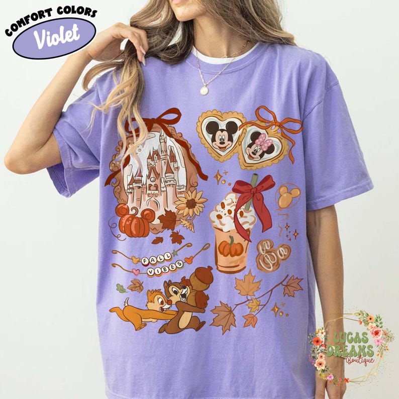 May include: Violet Comfort Colors t-shirt with a fall-themed graphic. The design includes a castle, pumpkins, Mickey and Minnie Mouse, Chip and Dale, and fall leaves. The shirt also has the words "Fall Vibes".