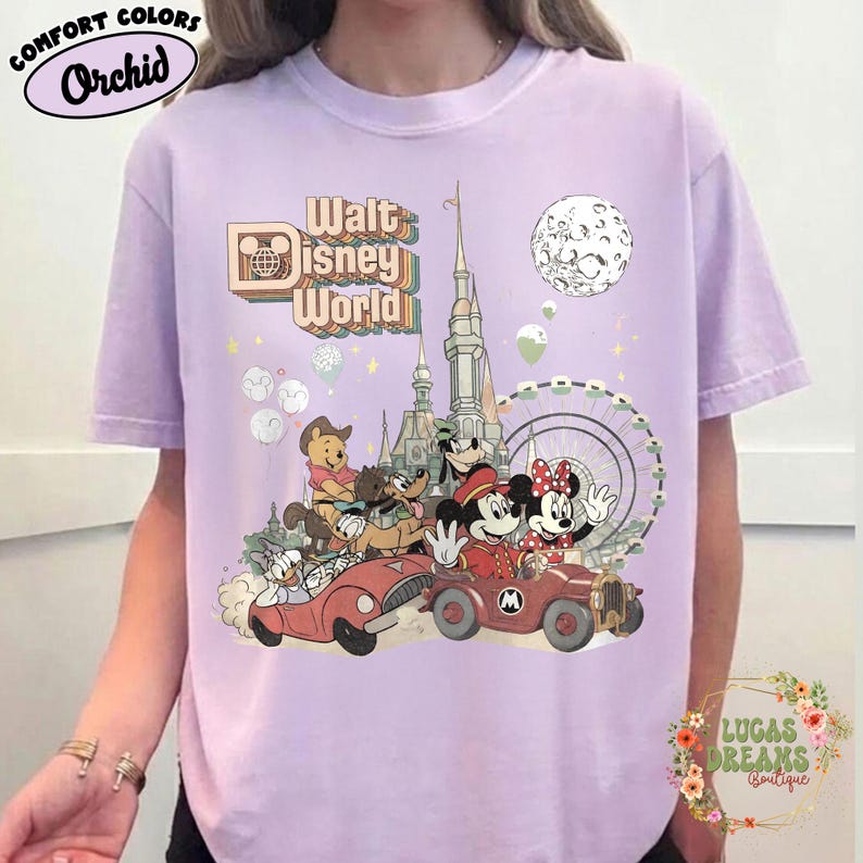 May include: Orchid Comfort Colors t-shirt featuring a colorful graphic of Disney characters in vintage style. The design includes Mickey and Minnie Mouse, Goofy, Donald Duck, and Winnie the Pooh, with the words "Walt Disney World".