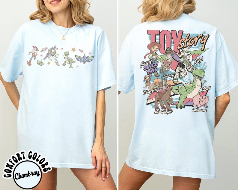 May include: Pale blue t-shirt with Toy Story characters on the front and back. The front shows Woody, Buzz Lightyear, and other characters. The back has a larger graphic with the words "Toy Story" and more characters.