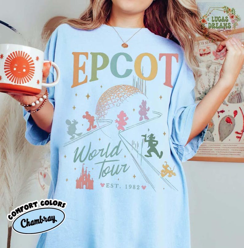Puede incluir: Camiseta azul claro con estampado gr&aacute;fico de EPCOT World Tour. La camiseta presenta el logotipo de EPCOT en colores pastel, con Mickey Mouse y sus amigos. Las palabras "World Tour" y "Est. 1982" tambi&eacute;n est&aacute;n impresas en la camiseta.