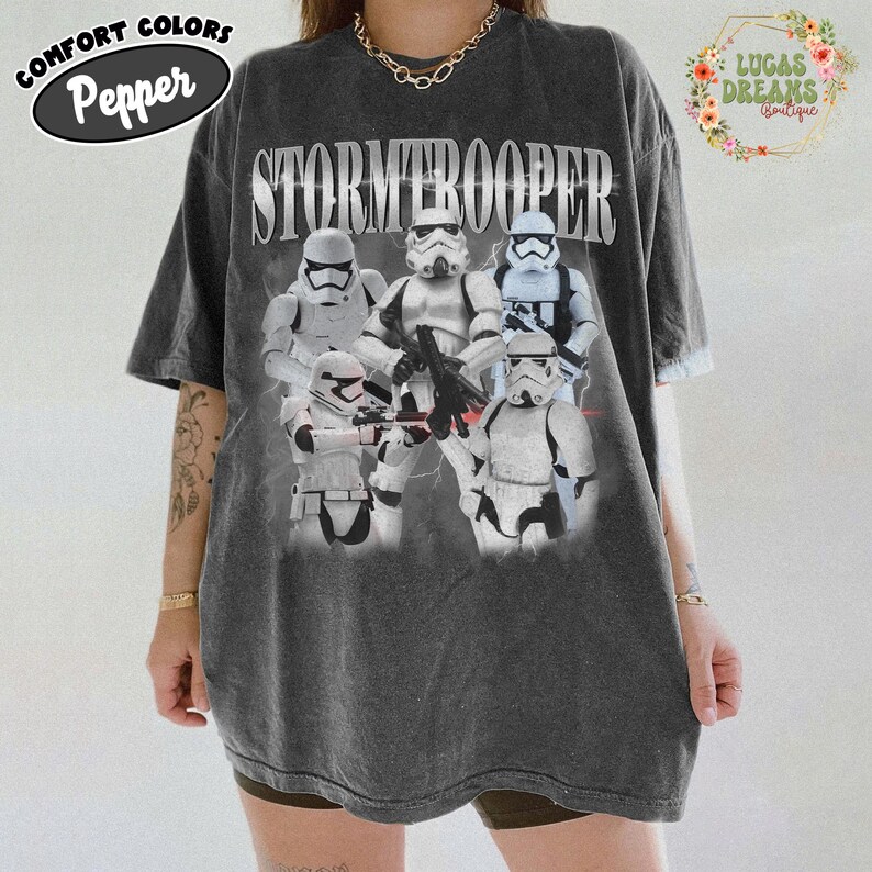 Puede incluir: Una camiseta de manga corta gris carb&oacute;n con un estampado gr&aacute;fico de cinco personajes Stormtrooper blancos de Star Wars. La palabra STORMTROOPER est&aacute; impresa en letras may&uacute;sculas blancas grandes sobre los personajes. Tiene cuello redondo.