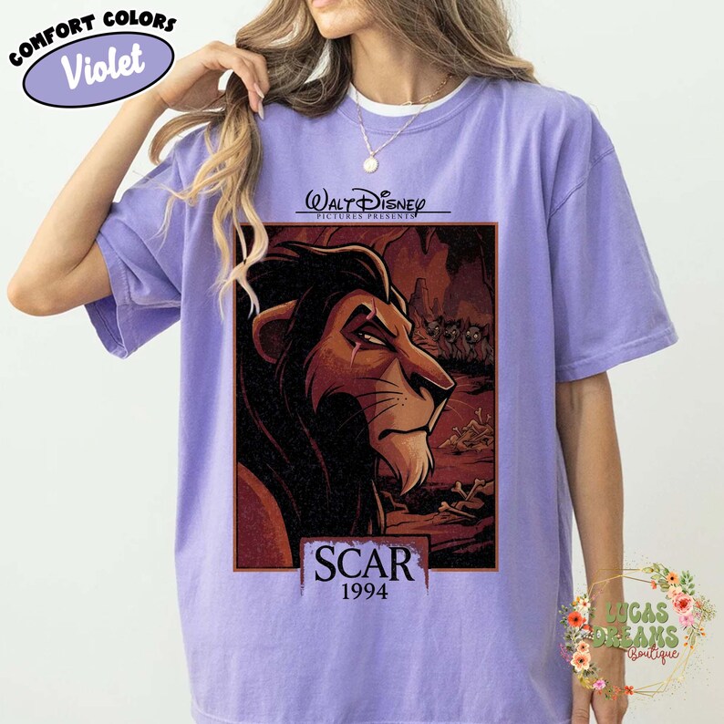 May include: A violet short-sleeve t-shirt featuring a graphic print of the character Scar from The Lion King. The design includes the text Walt Disney Pictures Presents, Scar, and 1994. The shirt has a crew neckline and a relaxed fit.