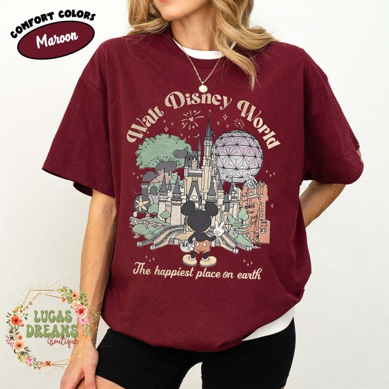 May include: Maroon t-shirt with a graphic of Mickey Mouse in front of a castle, with the text "Walt Disney World" and "The happiest place on earth". The shirt also has the text "Comfort Colors" and "Maroon".
