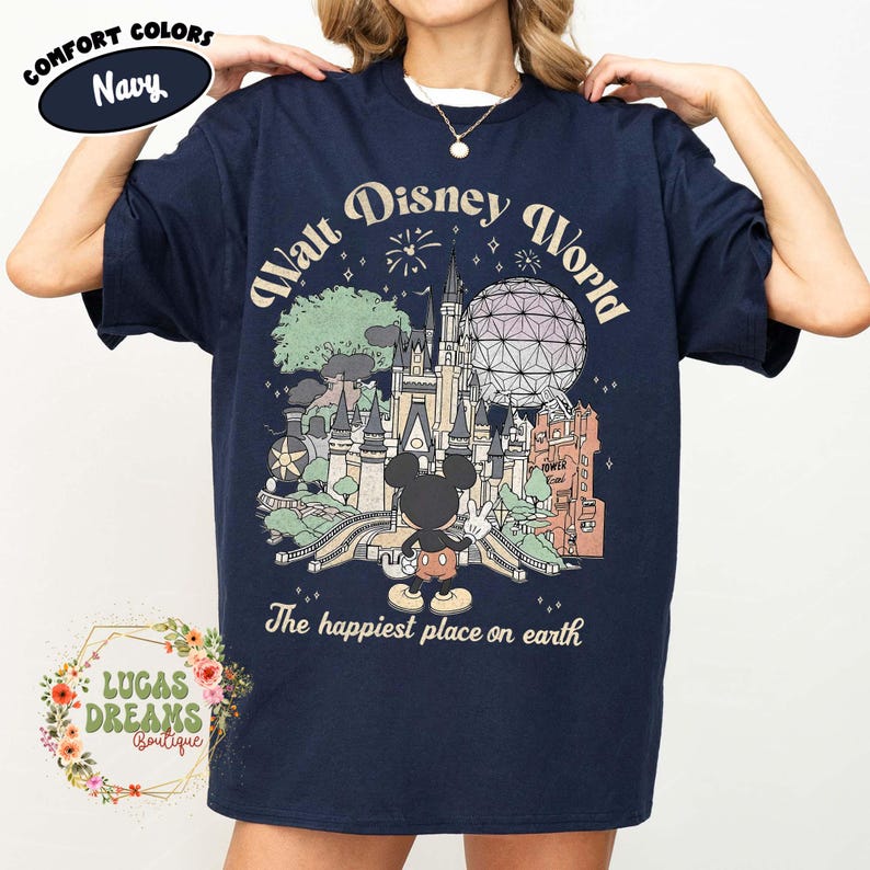 May include: Navy blue t-shirt featuring a vintage-style graphic of Walt Disney World with Mickey Mouse. The design includes the text "Walt Disney World" and "The happiest place on earth". The shirt also has the text "Comfort Colors" and "Navy".