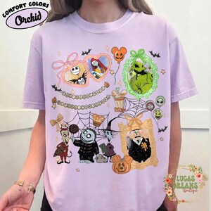 Puede incluir: Camiseta Orchid Comfort Colors con un gr&aacute;fico colorido de The Nightmare Before Christmas. El dise&ntilde;o incluye a Jack Skellington, Sally, Oogie Boogie y otros personajes en marcos decorativos, con murci&eacute;lagos y estrellas.