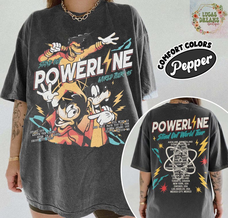 Puede incluir: Camiseta gris oscuro de Powerline World Tour con personajes de dibujos animados y gr&aacute;ficos de rayos. La parte delantera muestra el nombre de la banda y "Stand Out". La parte trasera enumera las ubicaciones de la gira. Hecho con Comfort Colors.