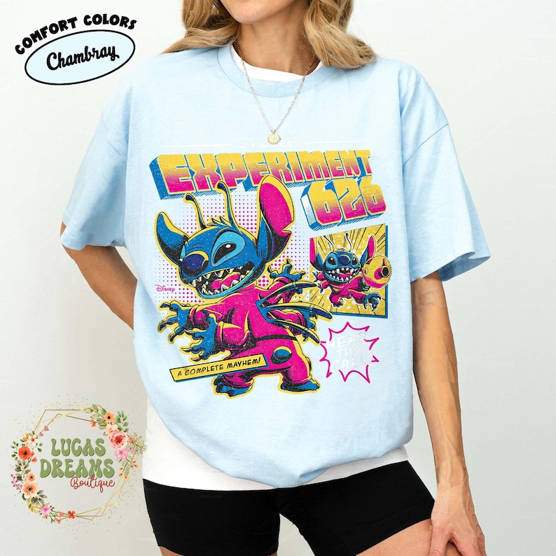 May include: Light blue t-shirt featuring a colorful graphic of the character Stitch from Disney's Lilo & Stitch. The design includes the text "EXPERIMENT 626" and "A COMPLETE MAYHEM!" in a retro style. The shirt is from the Comfort Colors brand.