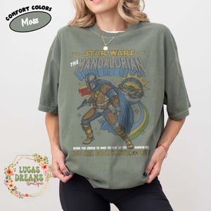 Puede incluir: Una camiseta de manga corta color verde musgo con un gr&aacute;fico de The Mandalorian y Grogu. El estampado incluye el texto STAR WARS THE MANDALORIAN y WHEN YOU CHOOSE TO WALK THE WAY OF THE MANDALORIAN YOU ARE BOTH HUNTER & PREY.