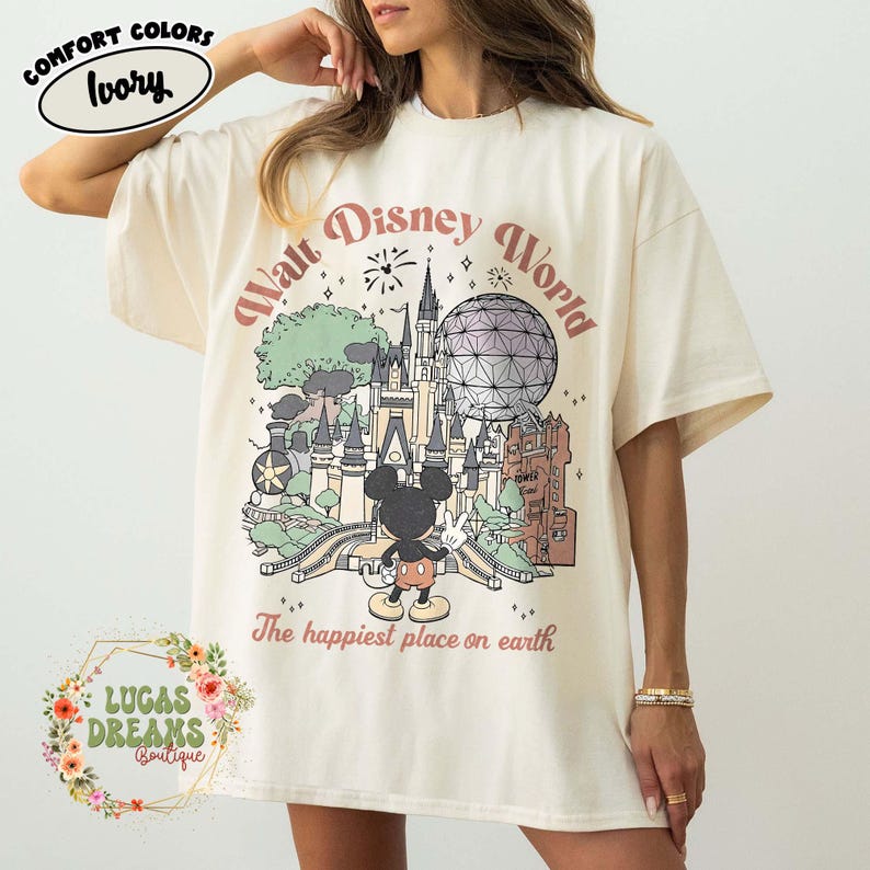 May include: Ivory-colored t-shirt with a graphic of the Walt Disney World castle, Spaceship Earth, and Mickey Mouse. The text "Walt Disney World" and "The happiest place on earth" are printed on the shirt. The shirt is from Lucas Dreams Boutique.