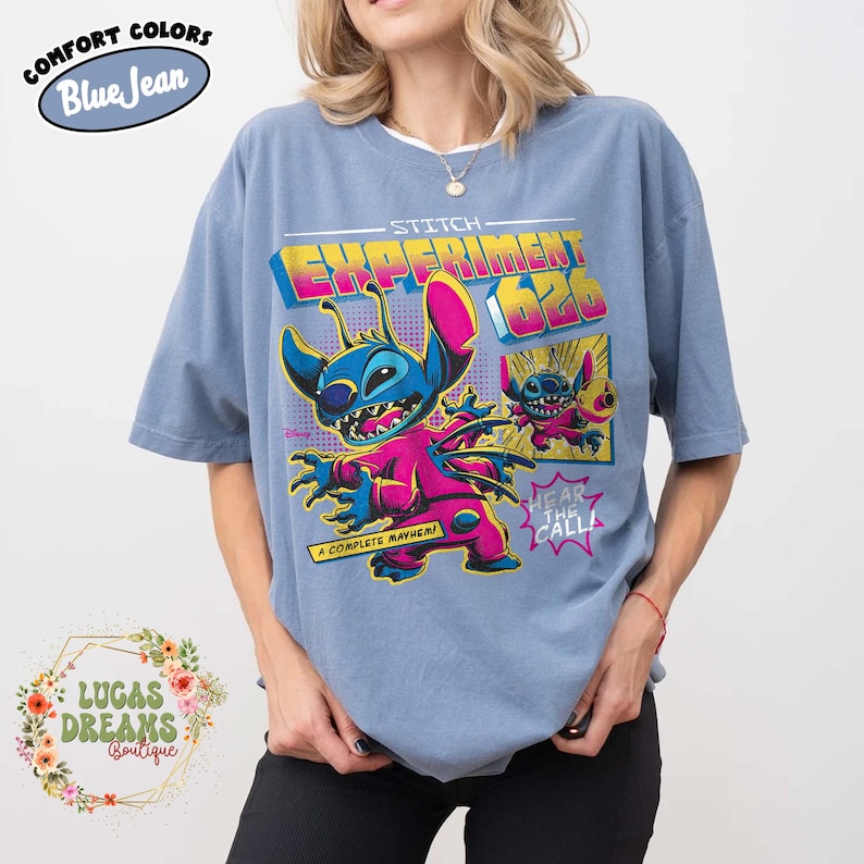 May include: Blue t-shirt with a graphic of Stitch from Lilo & Stitch. The design features Stitch in a pink jumpsuit with the text "Stitch Experiment 626" and "A Complete Mayhem!"