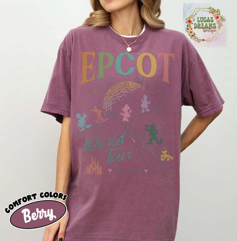 Puede incluir: Camiseta de color bayas con la palabra "EPCOT" en letras coloridas sobre un gr&aacute;fico de la geosfera Spaceship Earth y personajes de Disney. La camiseta tambi&eacute;n presenta las palabras "World Tour" y un gr&aacute;fico de castillo.
