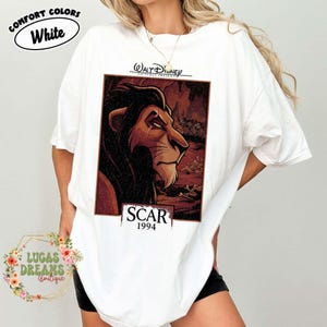 May include: A white short-sleeved t-shirt featuring a rectangular graphic print of the character Scar from The Lion King. The print includes the text Walt Disney Pictures Presents, Scar, and 1994. The shirt has a crew neckline and loose fit.