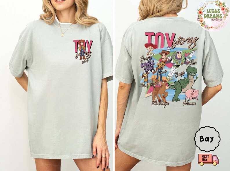 Peut inclure: T-shirt vert clair avec l'inscription "Toy Story" en rose et noir, et un dessin de Woody sur le devant. Le dos du t-shirt pr&eacute;sente divers personnages de Toy Story, dont Buzz l'&Eacute;clair et Rex.
