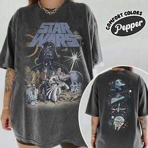 Puede incluir: Camiseta gráfica gris oscuro de Star Wars con Darth Vader y otros personajes. La parte delantera de la camiseta tiene el logotipo de Star Wars y una escena de la película. La parte trasera de la camiseta tiene un gráfico de la Estrella de la Muerte, X-wing y Halcón Milenario.