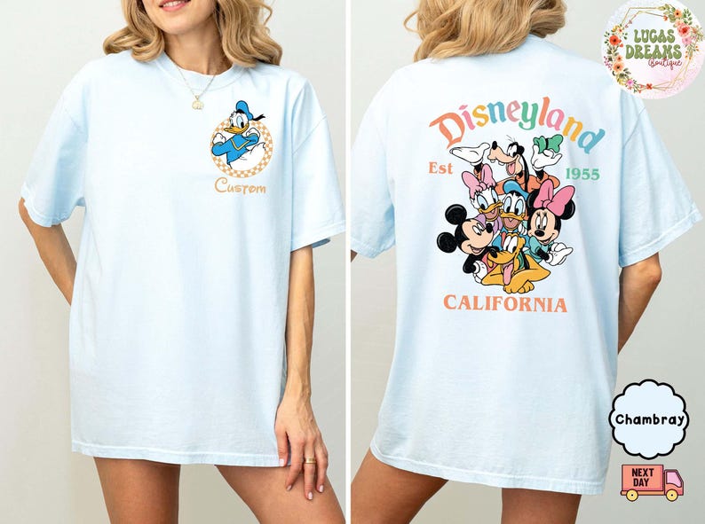 Puede incluir: Camiseta azul claro con Donald Duck en la parte delantera y un dise&ntilde;o de Disneylandia en la parte trasera. El dise&ntilde;o de Disneylandia incluye a Mickey Mouse, Minnie Mouse, Goofy, Donald Duck y Pluto. La camiseta tiene el texto "Disneyland Est 1955 California".