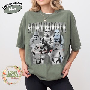 Puede incluir: Una camiseta de manga corta color verde musgo con un estampado gr&aacute;fico de cinco personajes Stormtrooper blancos de Star Wars. La palabra STORMTROOPER est&aacute; impresa en una fuente grande de estilo met&aacute;lico sobre los personajes. Cuello redondo.