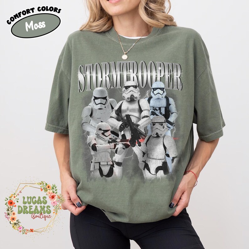 Puede incluir: Una camiseta de manga corta color verde musgo con un estampado gr&aacute;fico de cinco personajes Stormtrooper blancos de Star Wars. La palabra STORMTROOPER est&aacute; impresa en una fuente grande de estilo met&aacute;lico sobre los personajes. Cuello redondo.