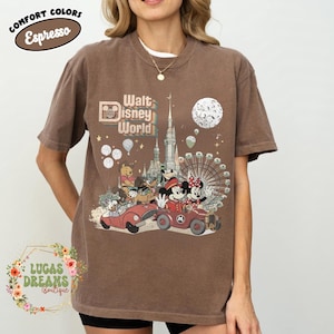May include: Brown t-shirt with a Walt Disney World graphic featuring Mickey and Minnie Mouse in vintage cars, a Ferris wheel, and a castle. The shirt also has the text "Comfort Colors Espresso".