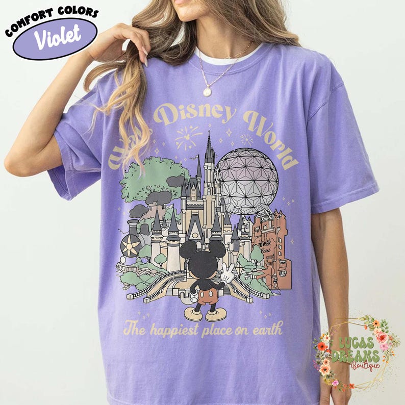May include: Violet Comfort Colors t-shirt featuring a Disney World graphic. The design includes a castle, Spaceship Earth, and Mickey Mouse. Text reads "Disney World" and "The happiest place on earth."