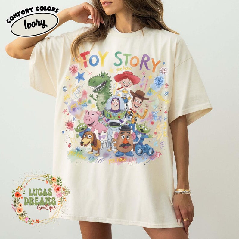 Pu&ograve; includere: T-shirt color avorio con la scritta "Toy Story" a lettere colorate e illustrazioni dei personaggi del film d'animazione. La maglietta ha girocollo e maniche corte. La maglietta &egrave; di Lucas Dreams Boutique.