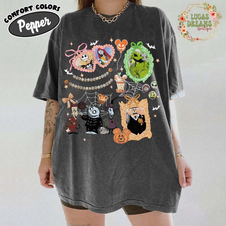Puede incluir: Camiseta gris oscuro con personajes de dibujos animados en marcos ornamentados, incluyendo Jack Skellington y Sally. La camiseta tiene las palabras "Comfort Colors Pepper" en un &oacute;valo negro y "Lucas Dreams Boutique" en una corona floral.