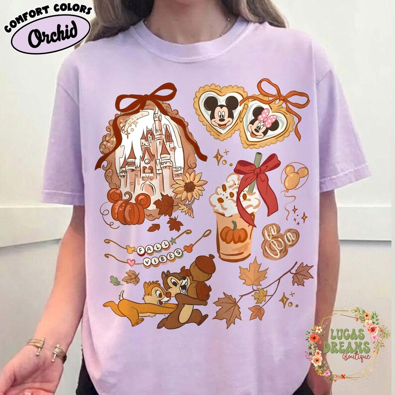 May include: Orchid Comfort Colors t-shirt featuring a fall-themed graphic with Disney characters, pumpkins, and autumn leaves. The design includes the text "Fall Vibes" and images of Chip and Dale. The shirt has a crew neck.