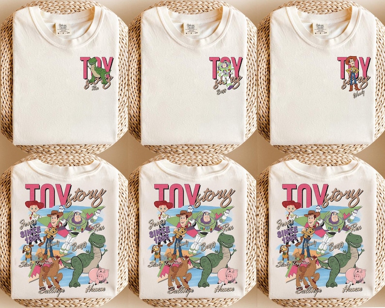 Peut inclure: T-shirts blanc cass&eacute; avec le texte "Toy Story" en rose et noir. Certains t-shirts ont un petit dessin de personnage, tandis que d'autres ont un dessin plus grand avec plusieurs personnages. Les t-shirts sont pr&eacute;sent&eacute;s sur une surface tiss&eacute;e.