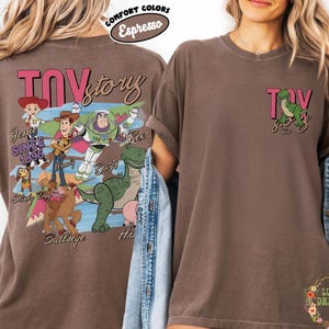 Peut inclure: T-shirt couleur expresso avec un motif Toy Story. Le dos du t-shirt affiche les mots "Toy Story" en rose, ainsi que des images de Woody, Buzz l'&Eacute;clair et d'autres personnages. La zone de la poche avant pr&eacute;sente un petit motif de Rex le dinosaure.