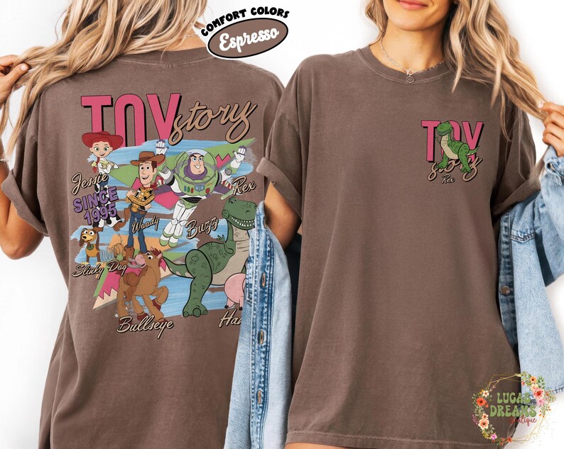 Peut inclure: T-shirt couleur expresso avec un motif Toy Story. Le dos du t-shirt affiche les mots "Toy Story" en rose, ainsi que des images de Woody, Buzz l'&Eacute;clair et d'autres personnages. La zone de la poche avant pr&eacute;sente un petit motif de Rex le dinosaure.