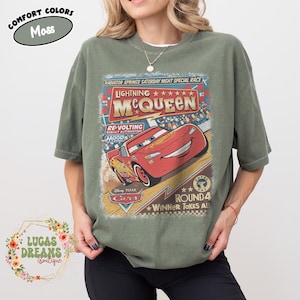 May include: Moss green t-shirt featuring a graphic of Lightning McQueen from the Disney Pixar Cars movie. The design includes the text "Lightning McQueen" and "Round 4 Winner Takes All". The shirt is a comfort colors style.