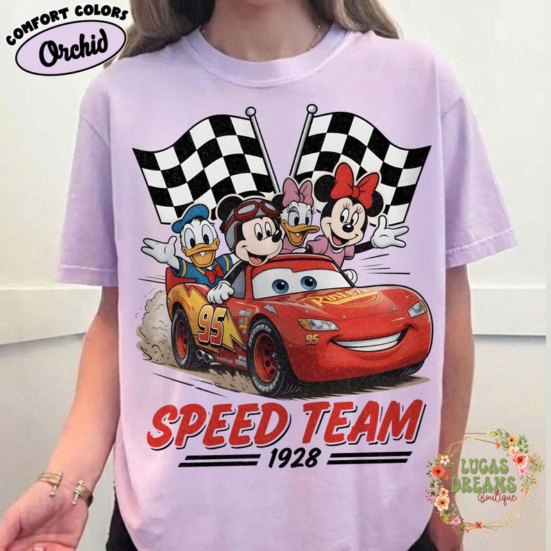 Op de afbeelding: Orchid Comfort Colors T-shirt met een afbeelding van Mickey Mouse, Donald Duck, Daisy Duck en Minnie Mouse in een rode raceauto. De auto heeft nummer 95, met de woorden "SPEED TEAM 1928" eronder.
