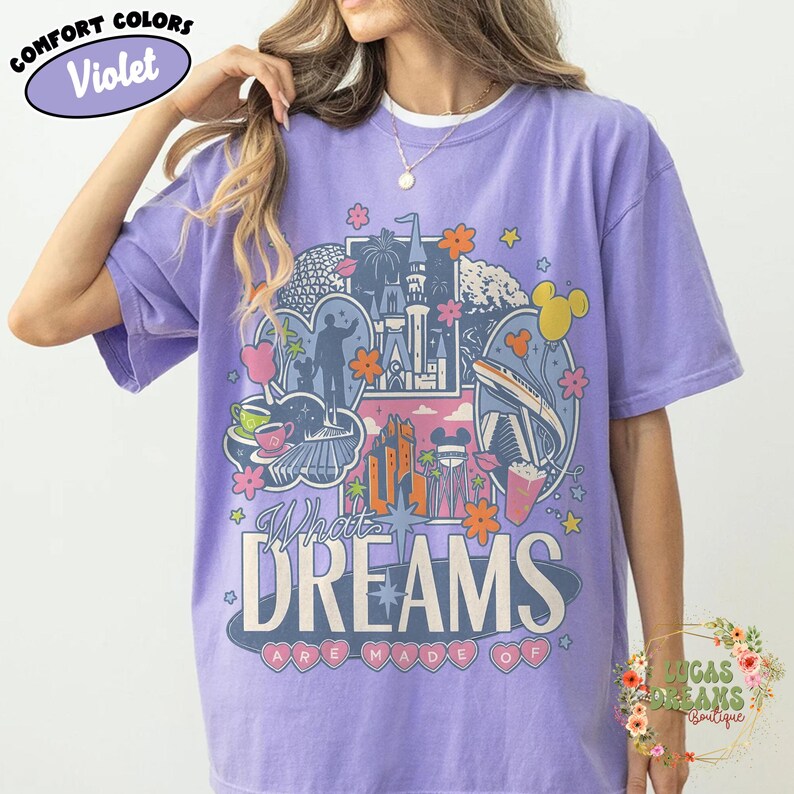 K&ouml;nnte beinhalten: Violettes Comfort Colors T-Shirt mit einem farbenfrohen Grafikdesign. Das Design zeigt ein Schloss, Blumen und den Text "What Dreams Are Made Of". Das T-Shirt hat eine helle violette Farbe.