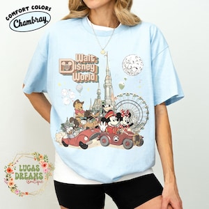 May include: Light blue t-shirt with a graphic of Mickey and Minnie Mouse in a red car, with other Disney characters and the words "Walt Disney World." The shirt also has the words "Comfort Colors Chambray" and "Lucas Dreams Boutique."