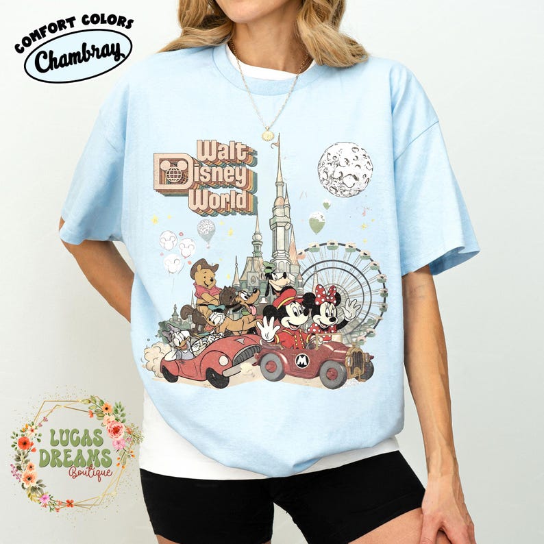 May include: Light blue t-shirt with a graphic of Mickey and Minnie Mouse in a red car, with other Disney characters and the words "Walt Disney World." The shirt also has the words "Comfort Colors Chambray" and "Lucas Dreams Boutique."