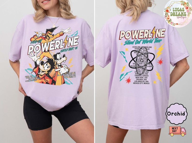 Puede incluir: Una camiseta de color lila con un gr&aacute;fico de los personajes de Powerline. El dise&ntilde;o frontal incluye la palabra "POWERLINE" y personajes de dibujos animados. La parte trasera de la camiseta enumera ciudades del "Stand Out World Tour".