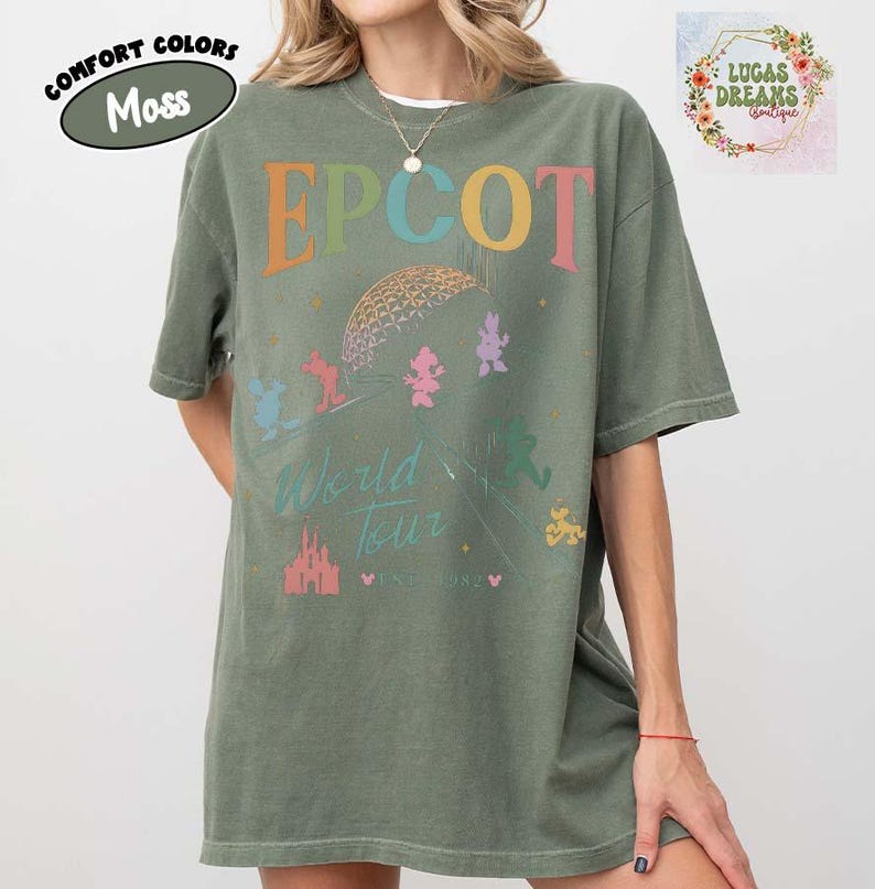 Puede incluir: Camiseta verde musgo con la palabra "EPCOT" en letras coloridas. La camiseta presenta un gr&aacute;fico de la bola EPCOT, personajes de Disney y las palabras "World Tour" y "Since 1982". Parte de la colecci&oacute;n Comfort Colors.