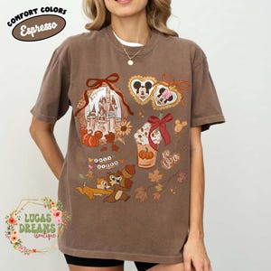 May include: Espresso-colored t-shirt featuring Disney-themed graphics. The design includes a castle, Mickey and Minnie Mouse hearts, a pumpkin spice latte, Chip and Dale, and fall leaves. The shirt has the text "COMFORT COLORS" and "Espresso".